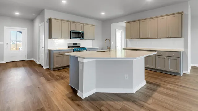 a kitchen with stainless steel appliances granite countertop a stove top oven a sink dishwasher and a refrigerator with wooden floor