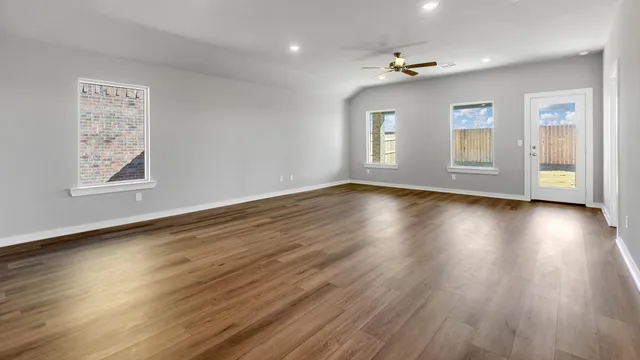 a view of an empty room with a window and wooden floor