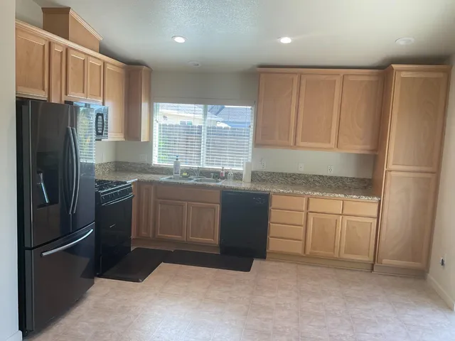 a kitchen with granite countertop stainless steel appliances a refrigerator and a sink