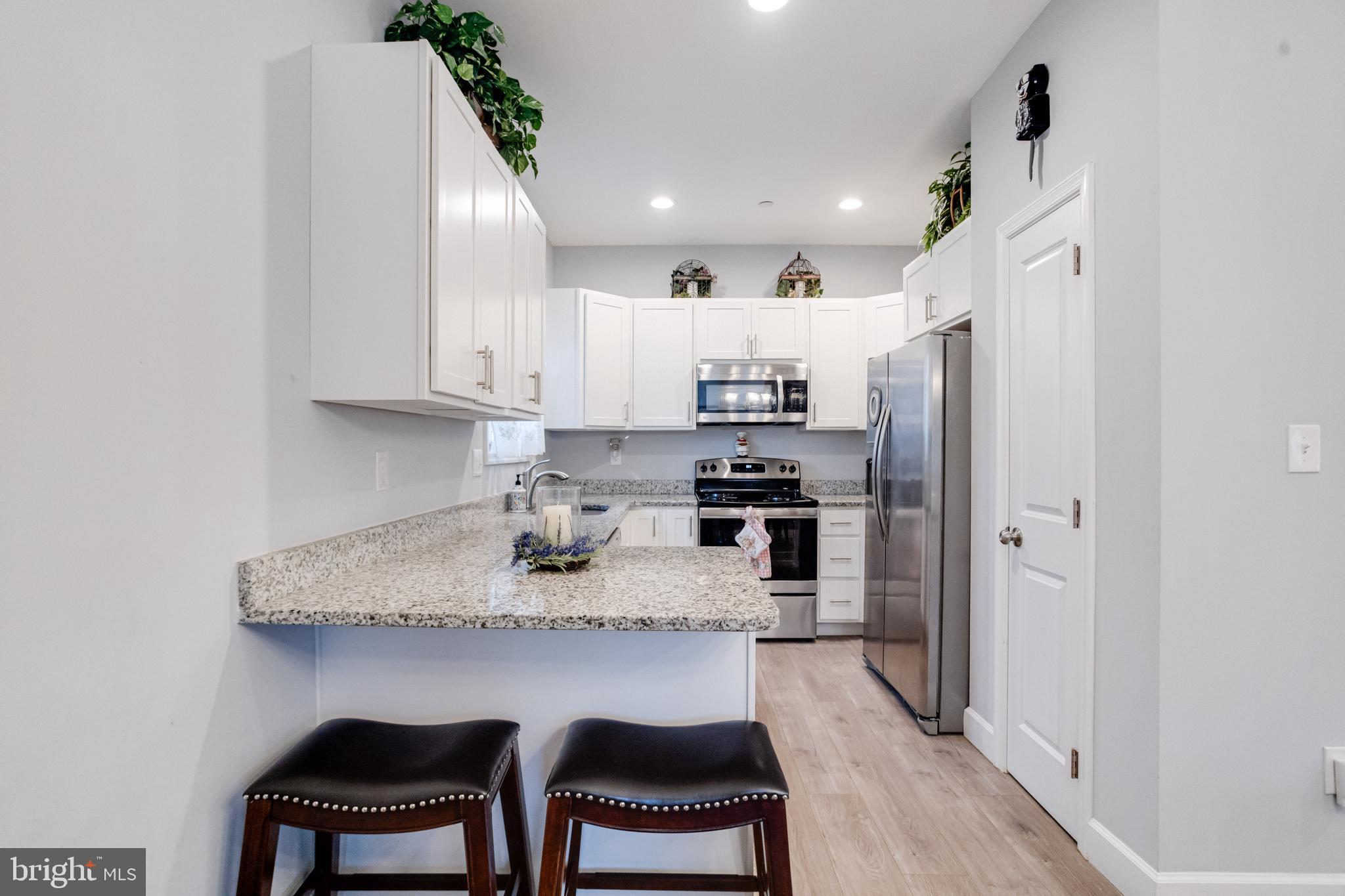 708 Hyde Park Road Essex, MD 21221 - Photo 19 of 65 a kitchen with stainless steel appliances granite countertop a refrigerator a sink dishwasher a stove a microwave oven with white cabinets and wooden floor