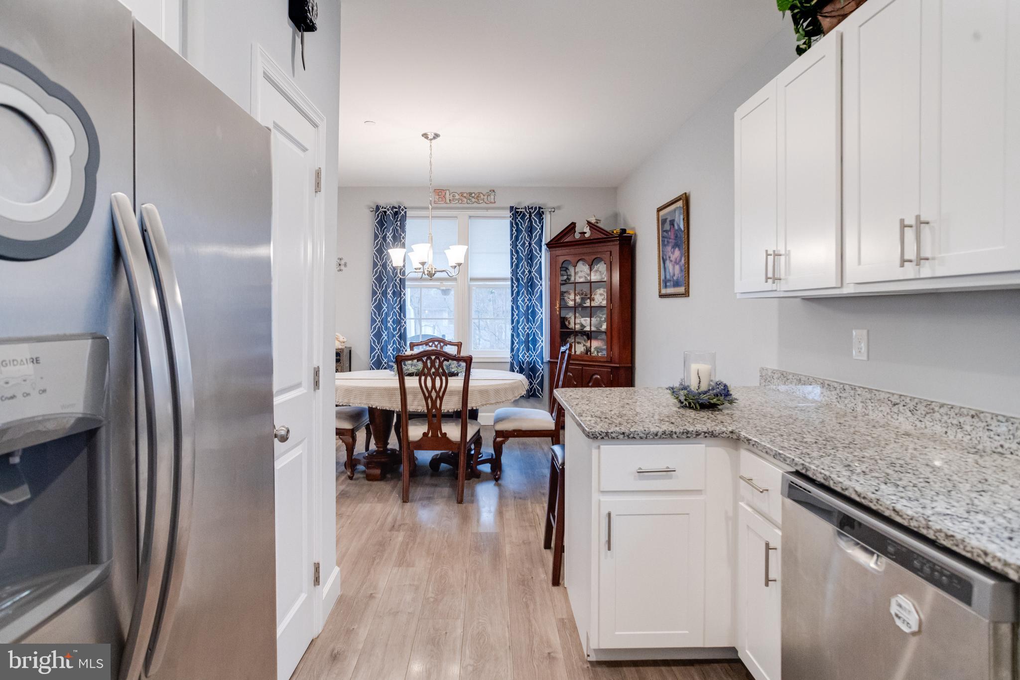 708 Hyde Park Road Essex, MD 21221 - Photo 24 of 65 a kitchen with stainless steel appliances granite countertop a refrigerator a sink dishwasher and white cabinets with wooden floor