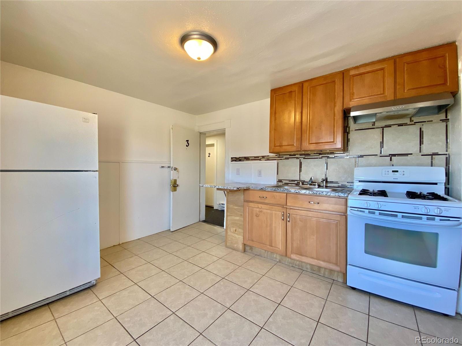 2422 West Vermijo Avenue, Unit 3 Colorado Springs, CO 80904 - Photo 2 of 7 a kitchen with a refrigerator sink and cabinets