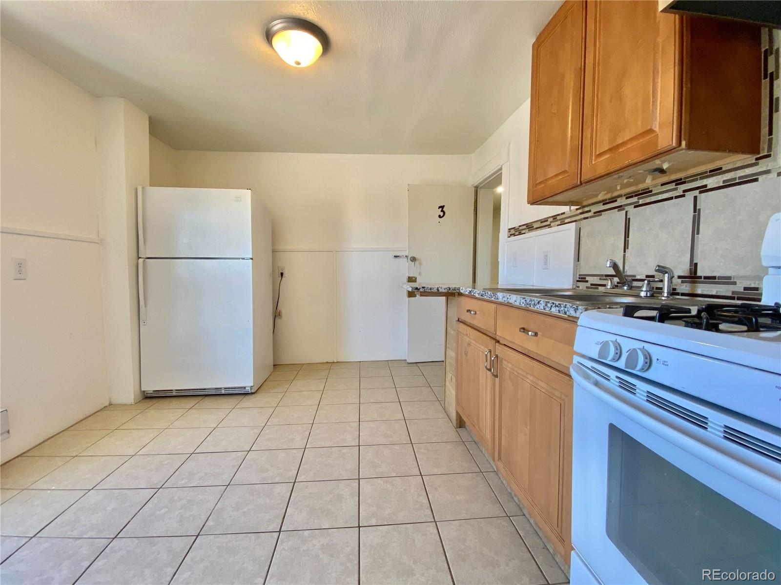 2422 West Vermijo Avenue, Unit 3 Colorado Springs, CO 80904 - Photo 3 of 7 a kitchen with a sink a refrigerator and cabinets