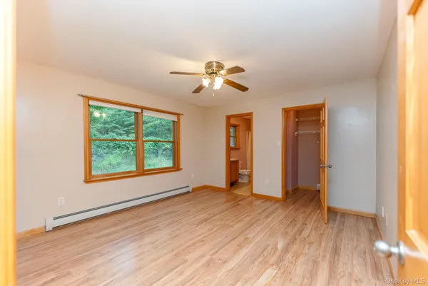 a view of an empty room with a window and wooden floor