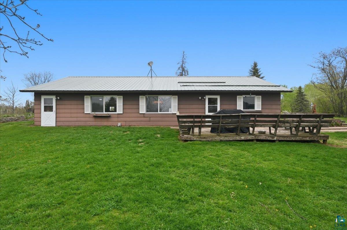 Expansive rear yard featuring a large wooden deck and a brown siding exterior