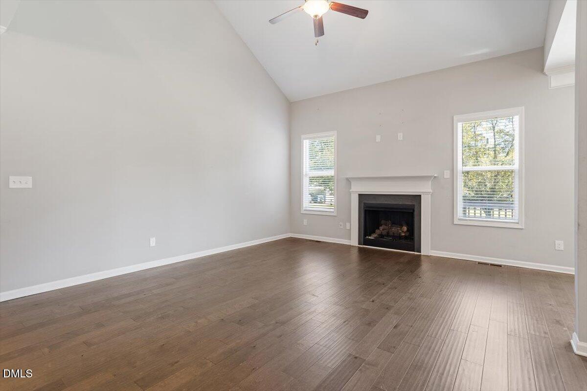 3361 Old Fairground Road Angier, NC 27501 - Photo 17 of 40 an empty room with wooden floor a fireplace and windows