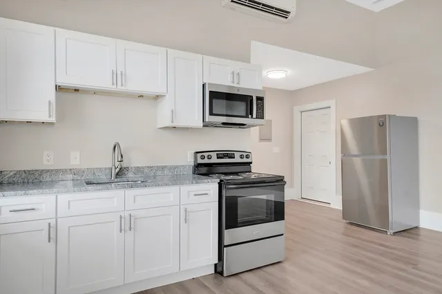 a kitchen with granite countertop white cabinets and stainless steel appliances