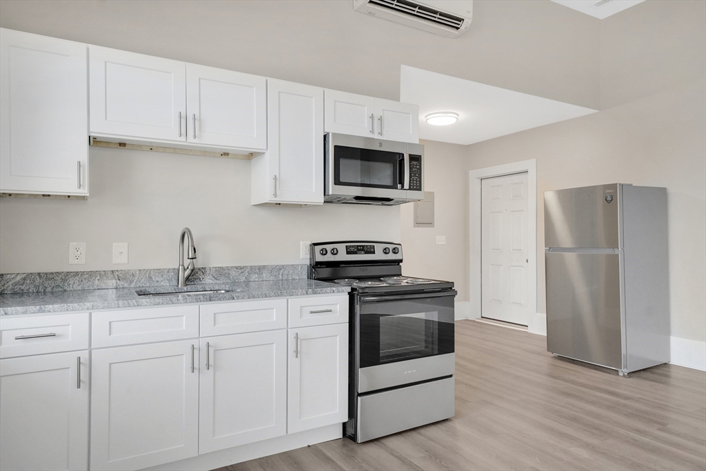 76-96 Maple Street Northampton, MA 01062 - Photo 4 of 22 a kitchen with granite countertop white cabinets and stainless steel appliances