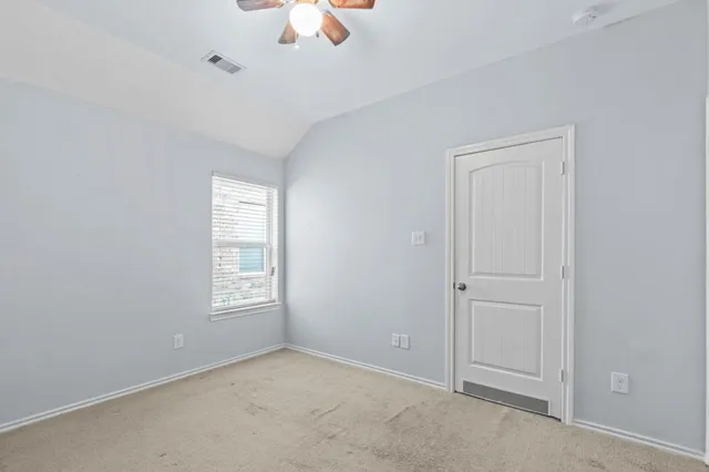 an empty room with windows and fan