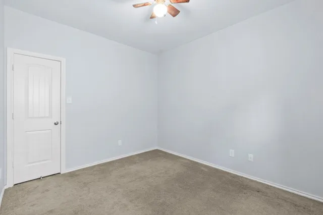 an empty room with a ceiling fan and carpet