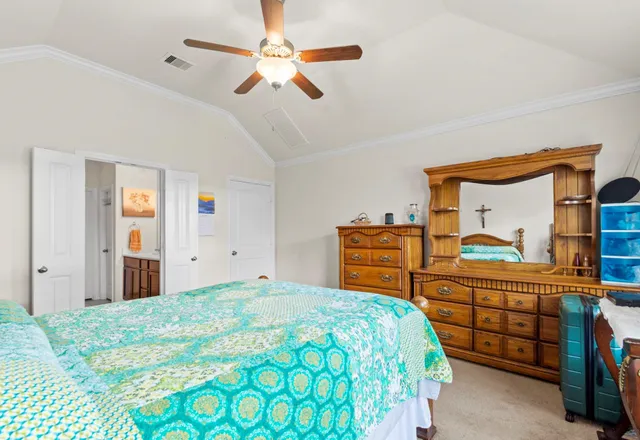 a bedroom with a bed a dresser and a chandelier