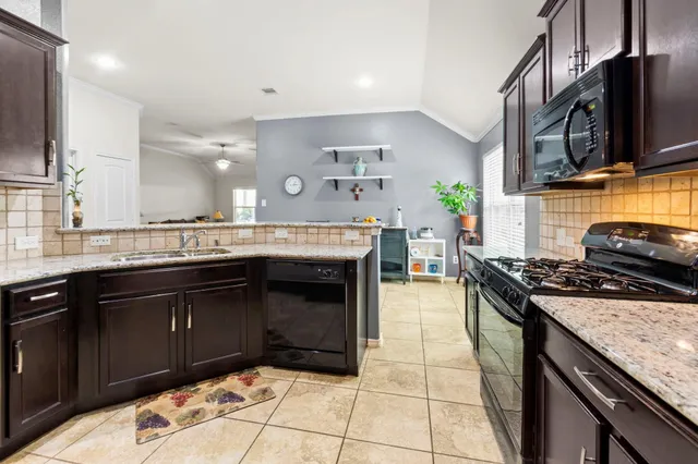 a kitchen with stainless steel appliances granite countertop a stove a sink and a microwave