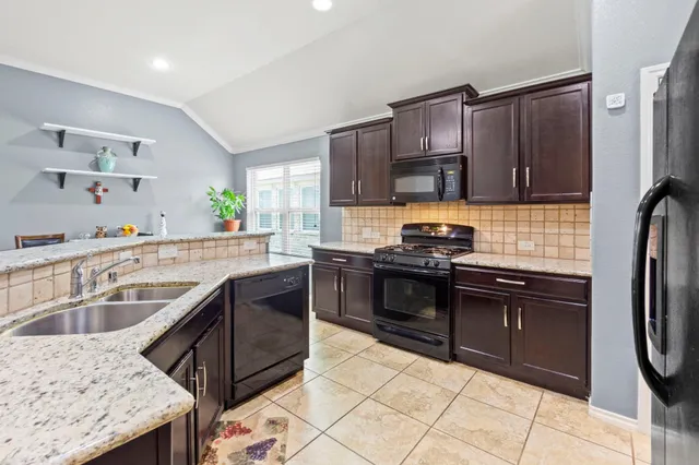a kitchen with granite countertop a sink stove and refrigerator