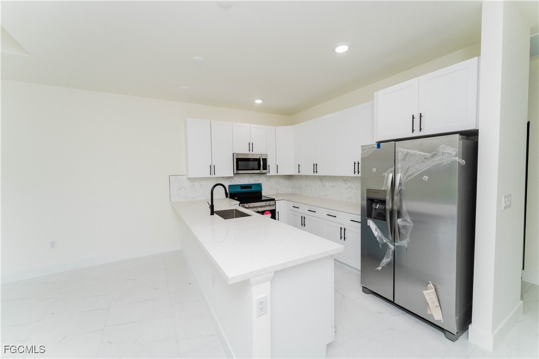 1171 Countess Avenue Lehigh Acres, FL 33974 - Photo 11 of 15 a kitchen with a refrigerator a sink and cabinets