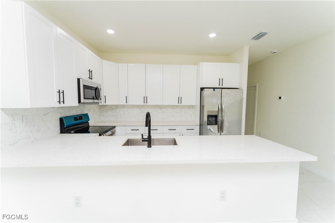 1171 Countess Avenue Lehigh Acres, FL 33974 - Photo 12 of 15 a kitchen with stainless steel appliances a refrigerator sink and microwave