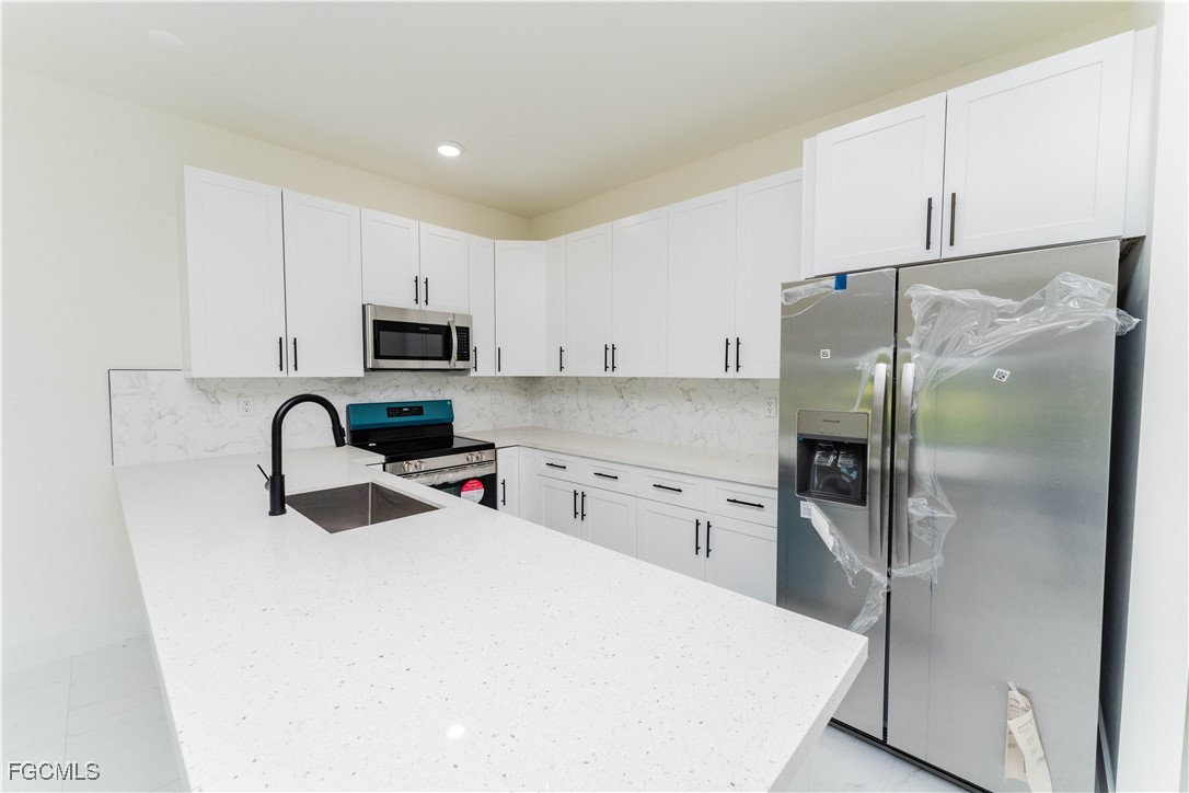 1171 Countess Avenue Lehigh Acres, FL 33974 - Photo 7 of 15 a kitchen with stainless steel appliances a refrigerator sink and microwave
