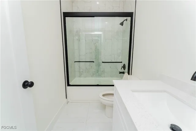 a bathroom with a granite countertop sink mirror vanity and toilet