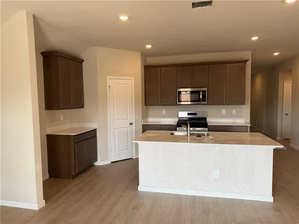 a large kitchen with a stove a sink and a microwave