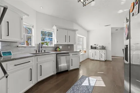 a kitchen with stainless steel appliances granite countertop a refrigerator sink and white cabinets