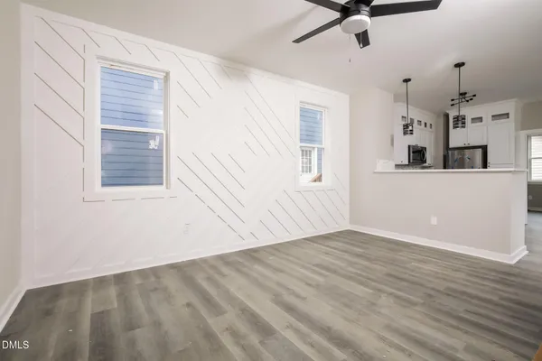 an empty room with wooden floor ceiling fan and windows