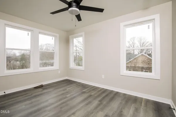 a view of an empty room with wooden floor and a window