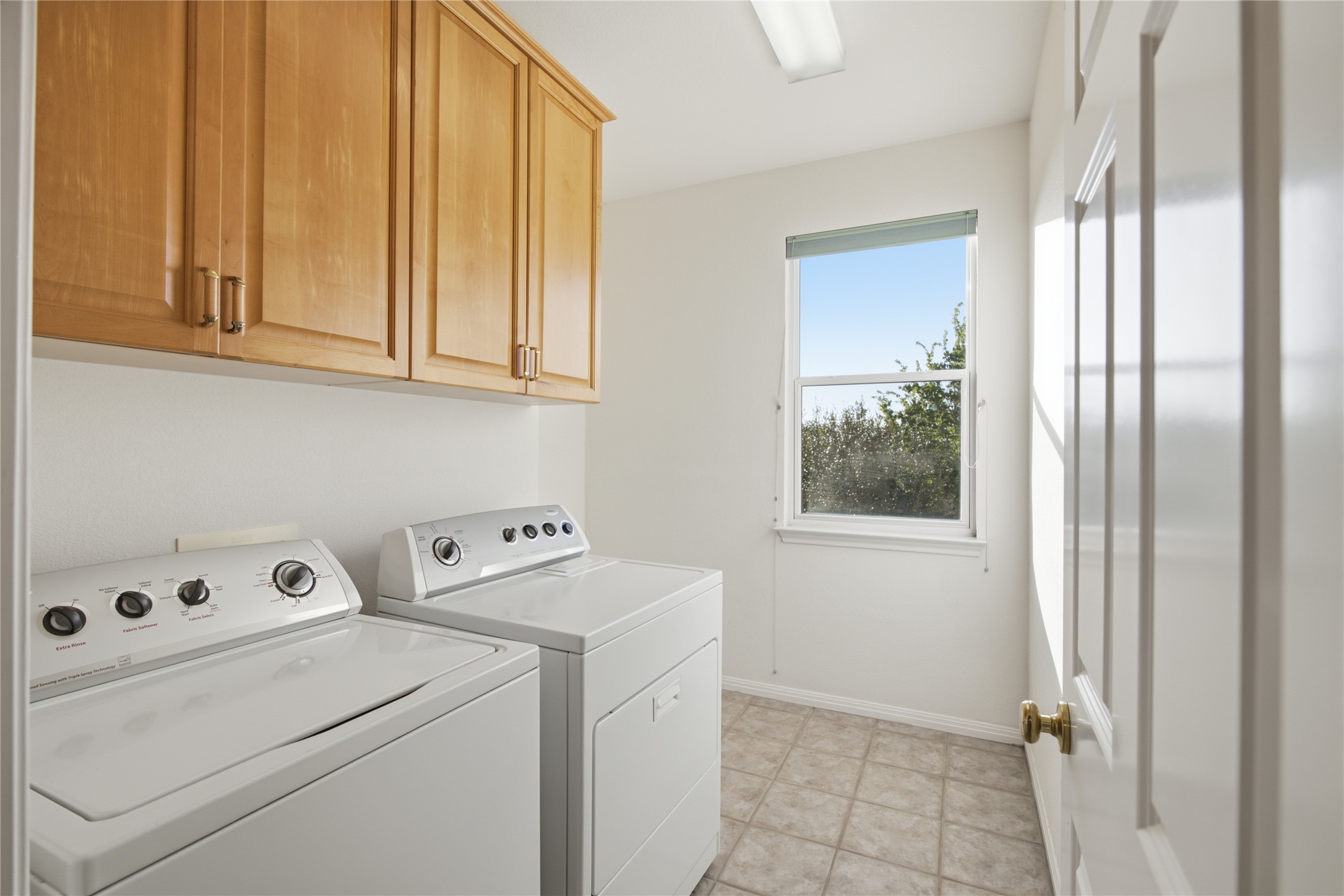 8204 Texas Plume Road Austin, TX 78759 - Photo 34 of 40 Ample storage cabinetry complements the functional laundry area, complete with washer and dryer units and a sun-filled window.