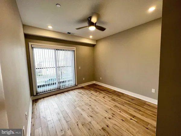a view of empty room with wooden floor and fan