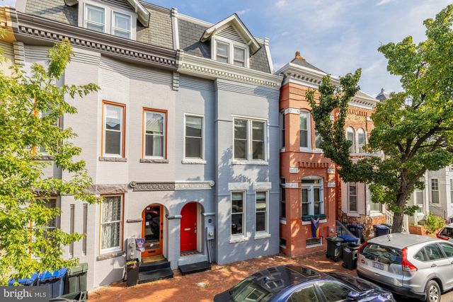 a view of a brick building with many windows and plants