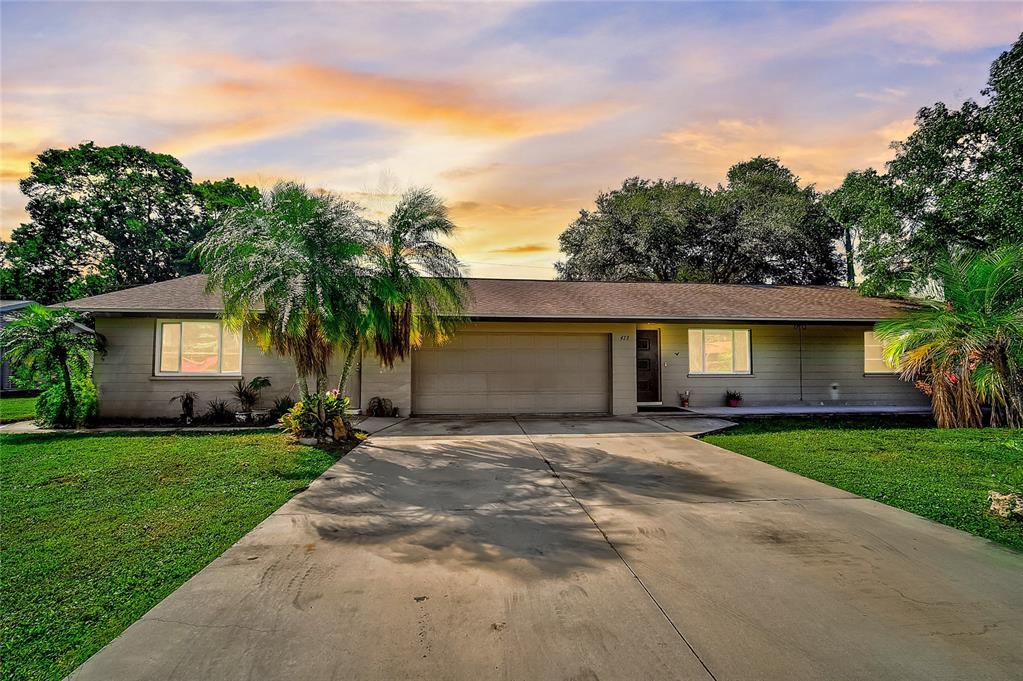 a front view of a house with a garden and trees
