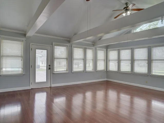 an empty room with wooden floor and windows