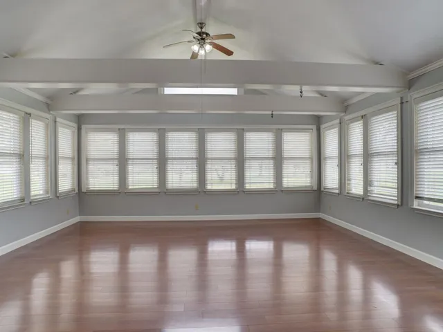 a view of empty room with wooden floor and fan