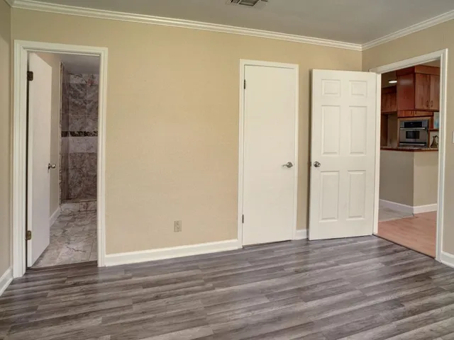 a view of an empty room with wooden floor & closet area