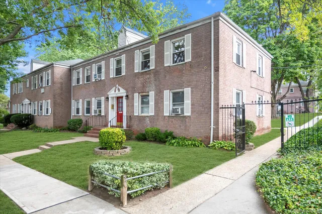 a view of a brick house with a yard and plants