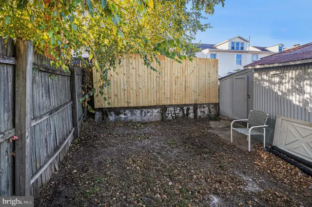 a view of a backyard with wooden fence and a bench