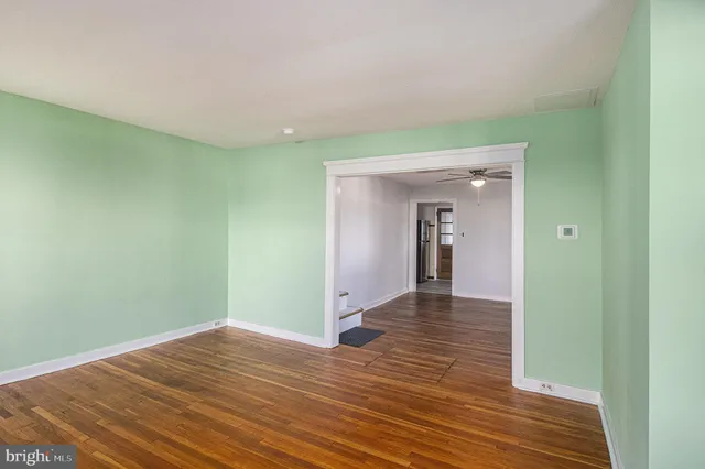 a view of a room with wooden floor and a ceiling fan