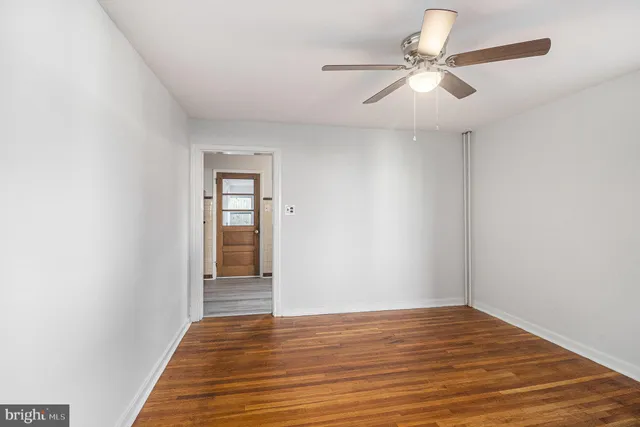 an empty room with wooden floor fan and windows