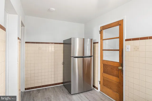 a view of a refrigerator in kitchen and an empty room
