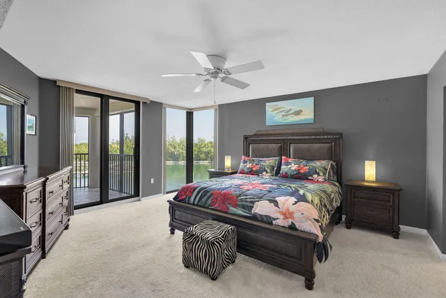 a bedroom with a bed large window with table and chair