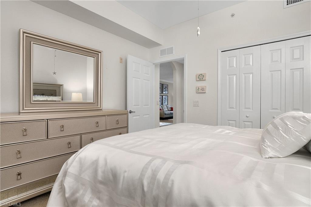 9719 Acqua Court, Unit 214 Naples, FL 34113 - Photo 21 of 50 a bedroom with a bed and a mirror