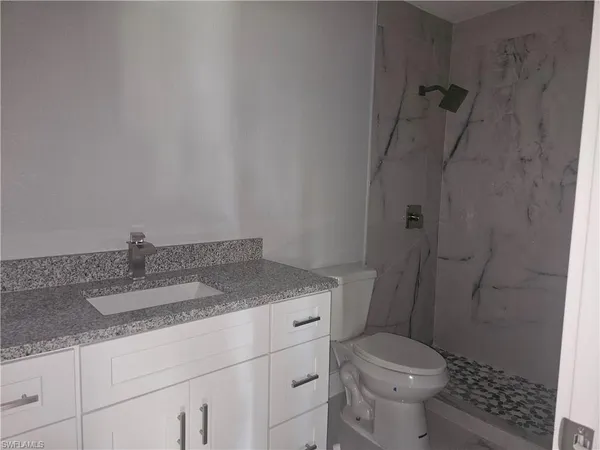 a bathroom with a granite countertop toilet and a sink