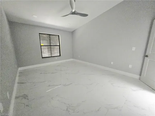 an empty room with windows and ceiling fan