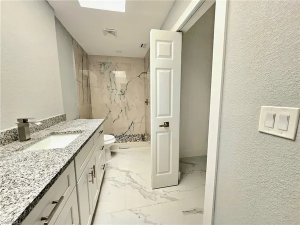 a spacious bathroom with a granite countertop sink and a mirror