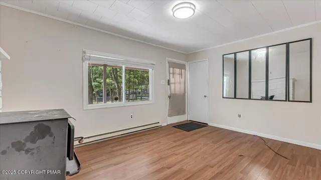 a view of an empty room with wooden floor and a window