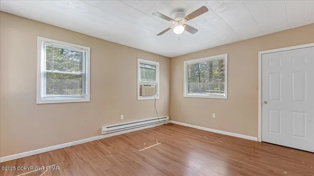 a view of empty room with wooden floor and fan