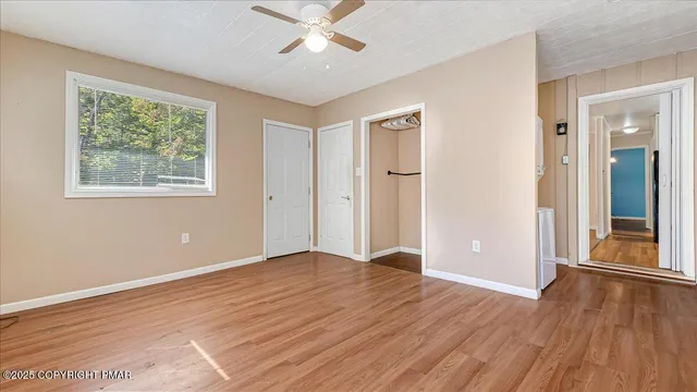 a view of an empty room with wooden floor and a window