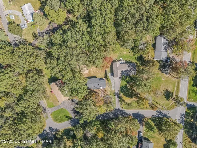 an aerial view of residential house with outdoor space and trees all around