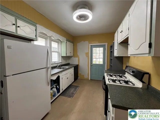 a kitchen with granite countertop white cabinets and refrigerator