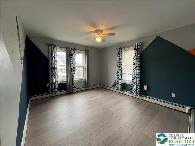 an empty room with wooden floor and fan
