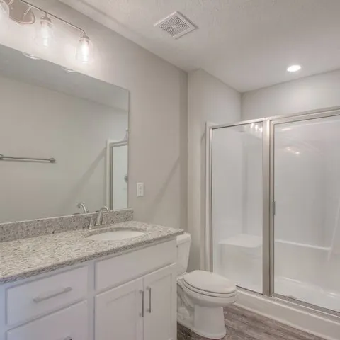 a bathroom with a granite countertop sink a toilet and a shower
