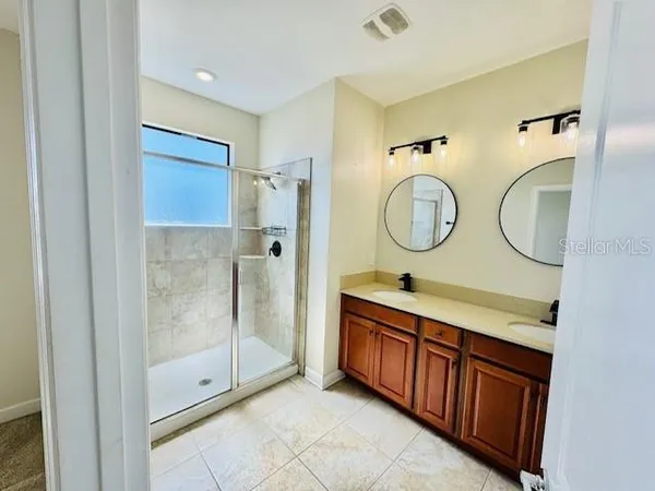 a bathroom with a double vanity sink mirror and shower